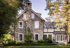 a large stone house surrounded by trees and grass