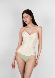 Sunlight Corset is a combination of sophistication and sunny light mood. This corset has a natural push-up effect due to the special arrangement of the bone layout and design. The corset is able to reduce the waist and hips, creating the perfect hourglass silhouette that makes you more feminine. The corset is made of high-quality French satin and transparent net hand-embroidered with sky blue and golden dandelions. It also has transparent paillettes (recycled plastic) imitating the morning dew. Hourglass Silhouette, Morning Dew, The Bone, Recycled Plastic, Sky Blue, Hand Embroidered, Push Up, Sunnies, Layout