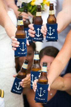 a group of people holding beer bottles in front of each other with an anchor on them