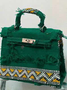 a green handbag sitting on top of a glass table next to a white wall