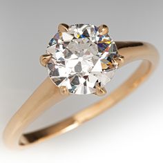 a yellow gold ring with a round brilliant diamond in the center, on a white background