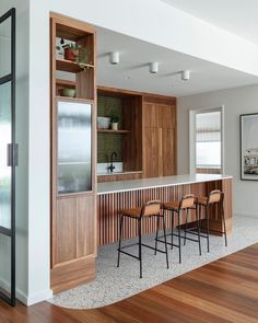 a kitchen with wooden cabinets and bar stools next to it on a hard wood floor