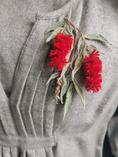 red flowers are attached to the back of a gray shirt