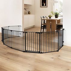 a large black metal dog gate in the middle of a room with wooden flooring