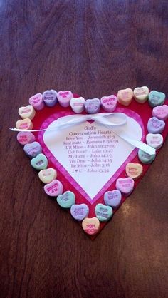 a heart shaped box with conversation hearts attached to it on top of a wooden table