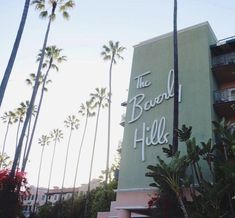 the sign for the hotel has palm trees in front of it and is very tall