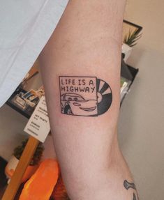 a person with a tattoo on their arm that reads life is a highway and has a car in it