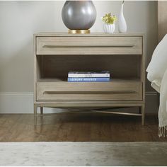 a nightstand with a book on it next to a bed