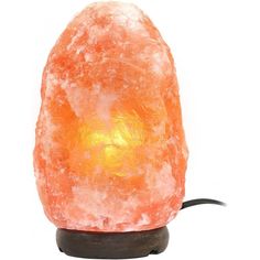 an orange himalayan salt lamp sitting on top of a wooden base