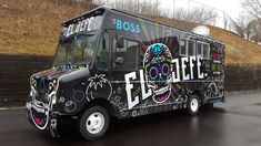 a decorated food truck is parked on the side of the road in front of a fence