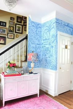 a living room with blue and white wallpaper on the walls, pink area rug