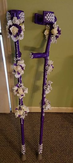 two purple and white decorated poles with flowers on each pole, one standing up against the wall