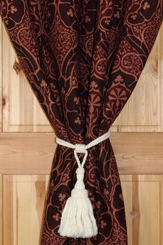 a curtain with a tassel hanging from it's side on a wooden wall