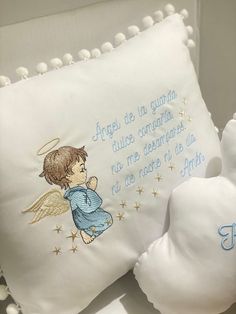 a white teddy bear with an embroidered angel pillow