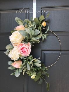 a wreath with flowers and greenery hanging on the front door for an elegant look