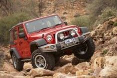 a red jeep driving on rocks in the desert