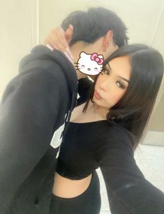 a man and woman taking a selfie in front of a mirror with an hello kitty sticker on it