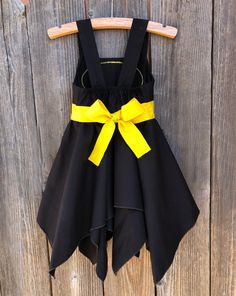 a black and yellow dress hanging on a wooden wall