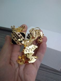 a person is holding some gold jewelry in their hand and it looks like they are wearing crowns