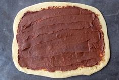 a chocolate frosted pastry sitting on top of a table next to a pan filled with batter