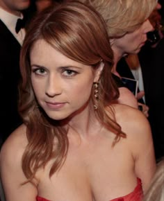 a woman in a red strapless dress at an event with other people around her