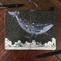 a notebook with a drawing of a whale and stars in the night sky on it