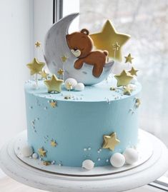 a blue cake with stars and a teddy bear on top