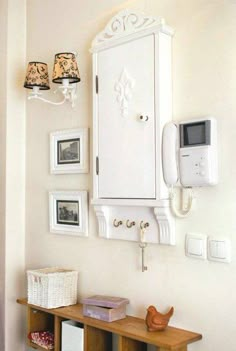 a white cabinet mounted to the side of a wall next to pictures and a phone