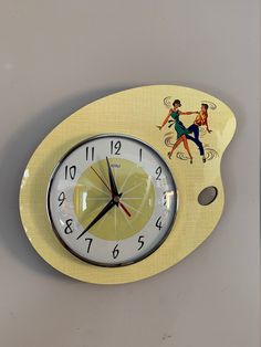 a clock with an image of a man and woman dancing on it's side