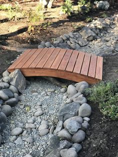 a wooden bench sitting on top of a pile of rocks next to a river bed