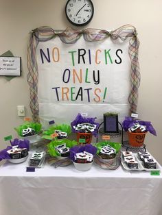 a table topped with lots of cupcakes covered in frosting next to a sign that says no tricks only treats