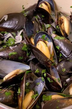 a bowl full of steamed mussels with parsley