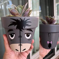 two potted plants with faces painted on them are being held in front of a window