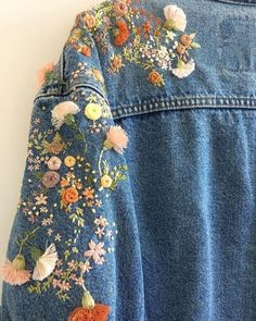 the back of a jean jacket with flowers on it