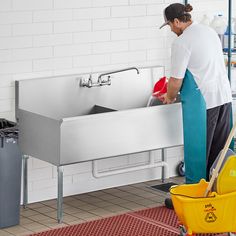 a man is washing his hands in the sink with a yellow mop and bucket