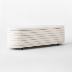 an upholstered bench made out of white wool with black legs and wooden feet