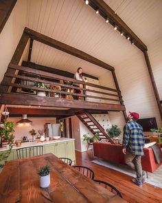 a man standing in the middle of a living room next to a kitchen and loft