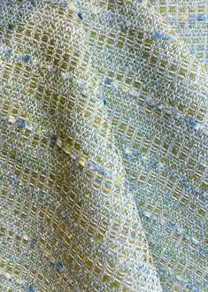 a close up view of a fabric with small squares on the side and green, blue, yellow, and white colors