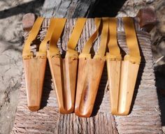 four wooden utensils sitting on top of a piece of wood next to a tree