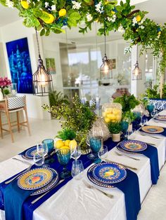 the table is set with blue and white plates, silverware, lemons, and greenery