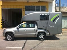 a silver truck parked in front of a yellow building