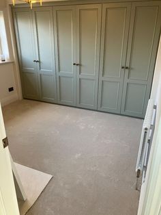 an empty room with green cupboards and carpeted flooring in the foreground