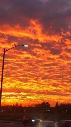 the sun is setting over some cars on the road