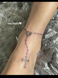 a woman's foot with a rosary and heart tattoo on the side of her leg