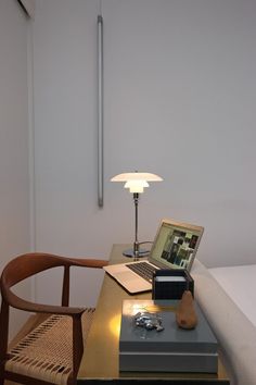 a laptop computer sitting on top of a wooden desk next to a lamp and chair