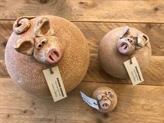 three ceramic pigs with tags on them sitting on a wooden floor next to each other