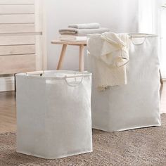 two white storage bags sitting on top of a rug next to a wooden table and chair