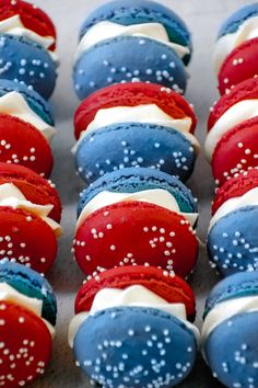 red, white and blue cupcakes with sprinkles are arranged on a table