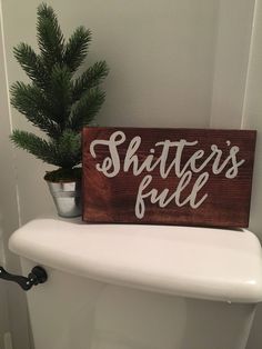 a wooden sign that says shitter's full on top of a toilet in a bathroom