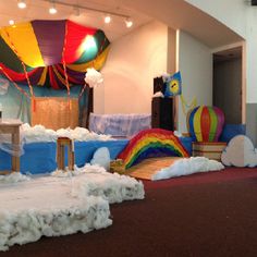 an indoor play area with fake clouds, rainbows and hot air balloons in the background